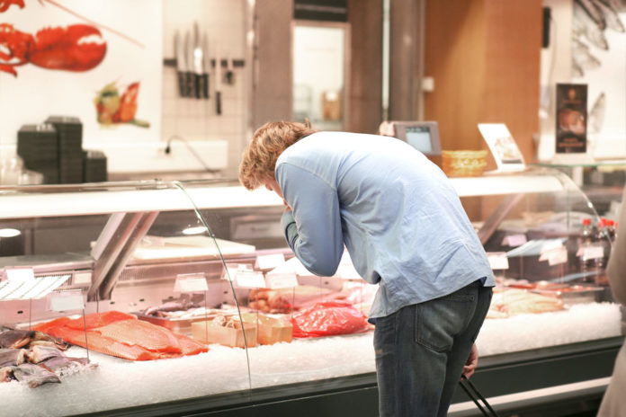 Man shopping for fresh fish seafood in supermarket