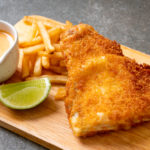 Air fryer fish and chips dish with sauce and lime