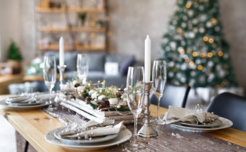 Table set with festive adornments and christmas tree in background