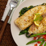 Baked tilapia on a bed of cooked spinach with a side of asparagus