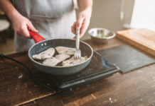 Man cooking fish fillets in a frying pan