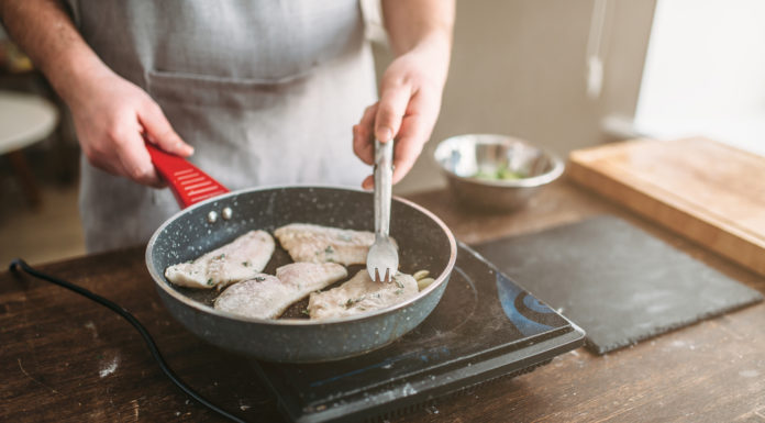 Man cooking fish fillets in a frying pan
